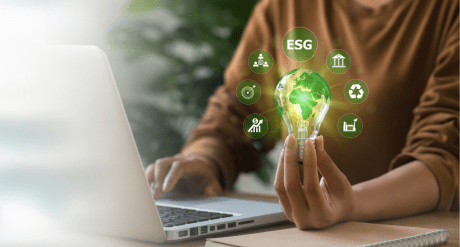 Woman's hand holding a lightbulb surrounded by ESG icons - concept for ESG 2024 A Year in Review
